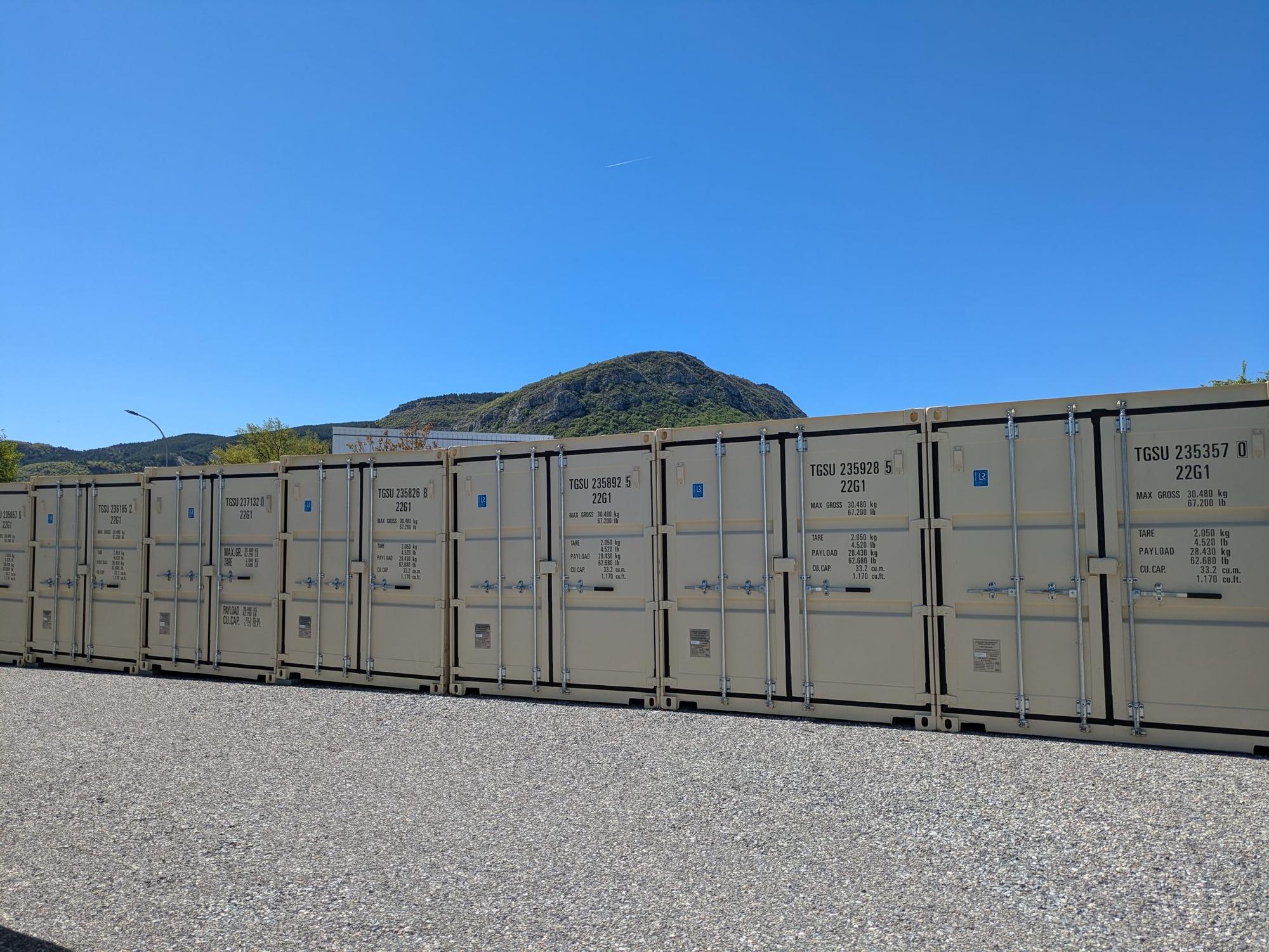 Rangée de conteneurs de stockage beiges des Box Martin, montagne des Hautes-Alpes en arrière-plan