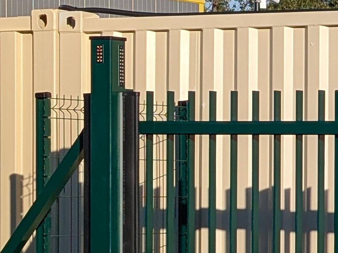 Bardage d’un conteneur de stockage beige, portail vert du site
